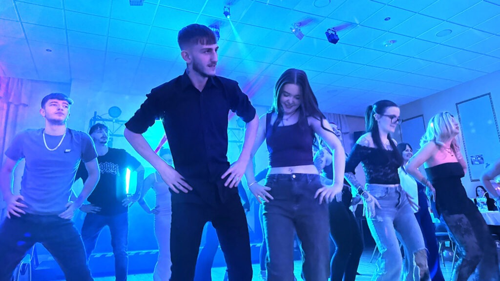 People dancing to Macarena with a blue colour wash from the disco lights